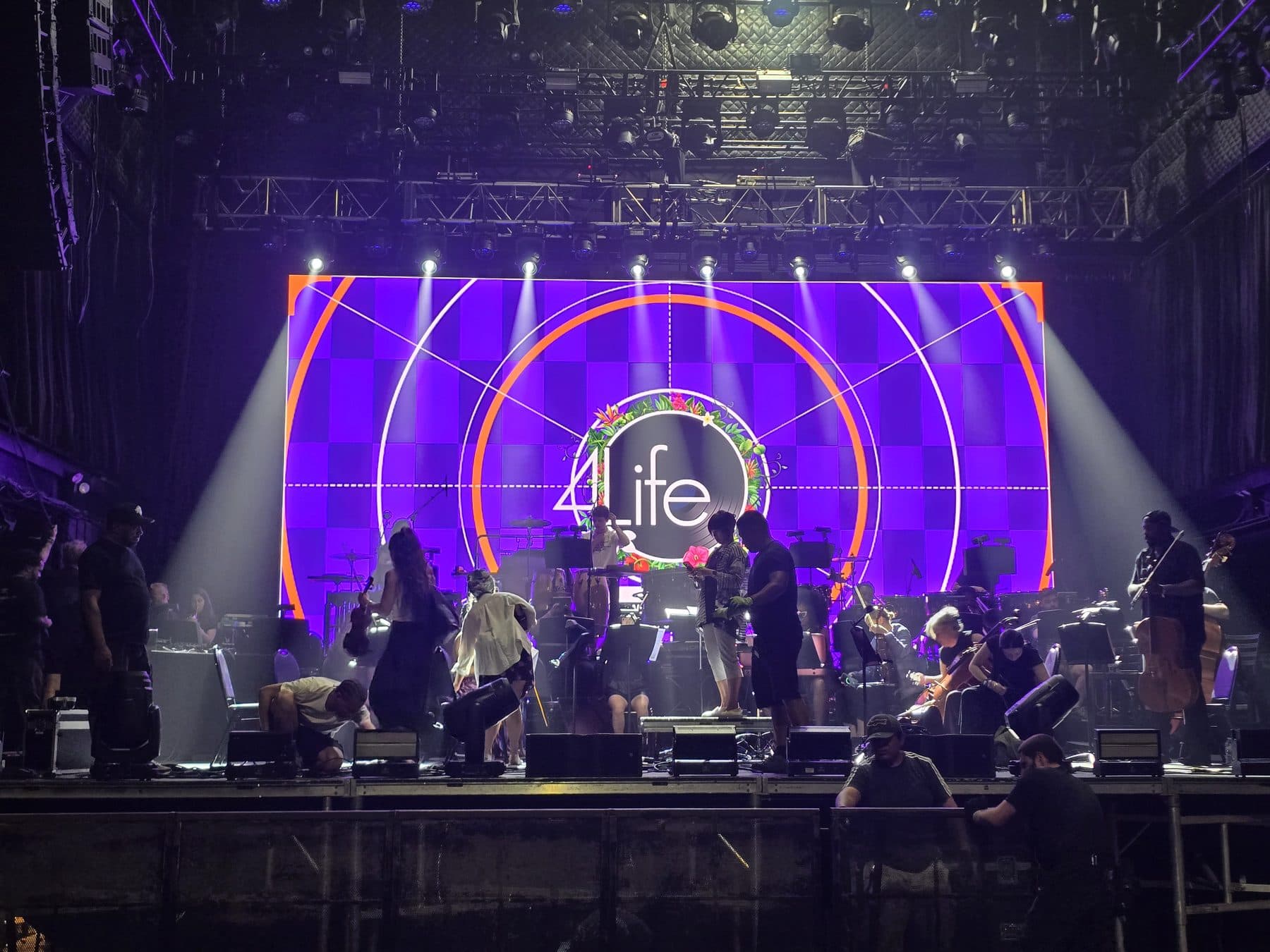 Amphitheater mainstage LED wall lit during a build, orchestra and crew on deck
