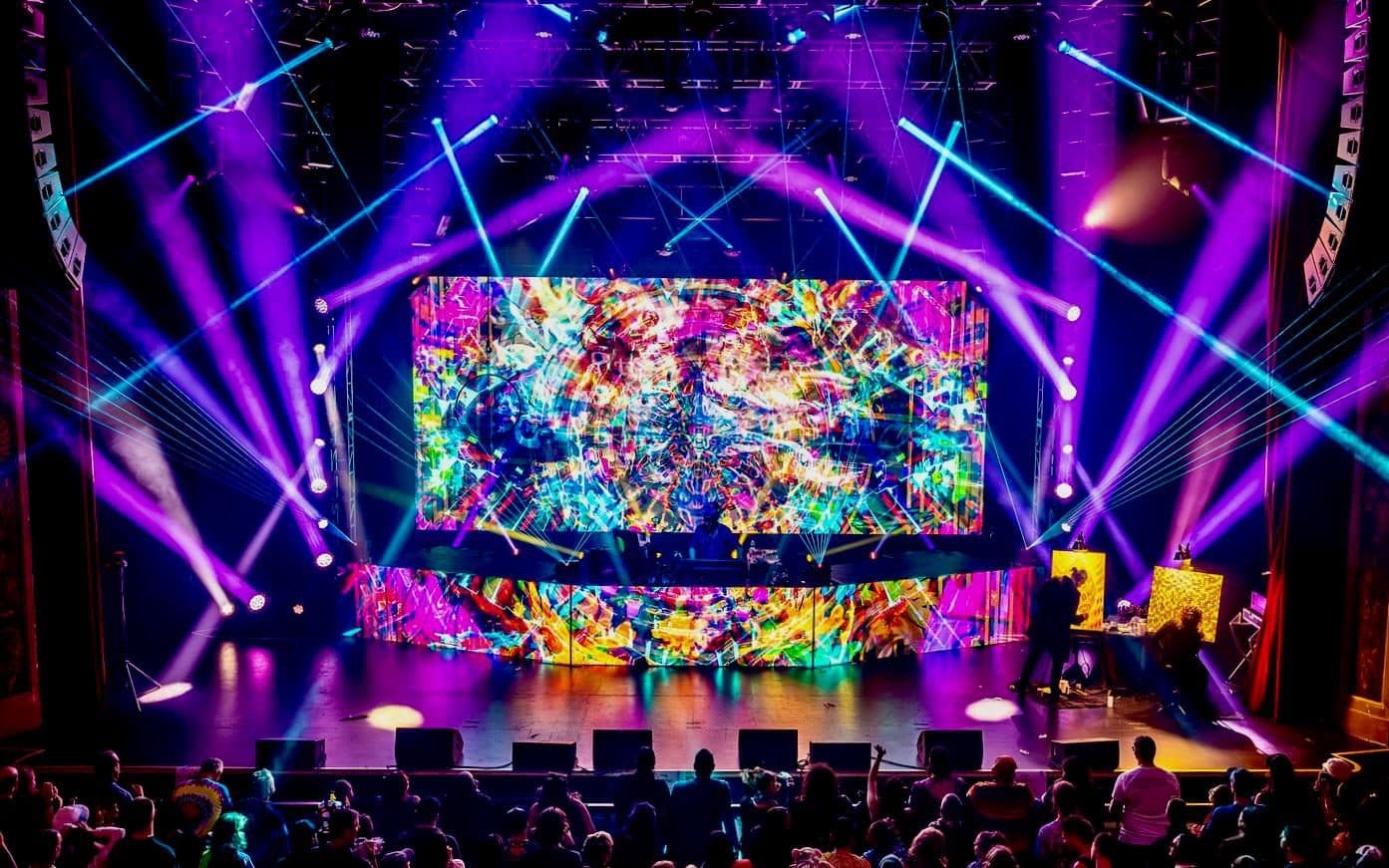 Wide LED wall anchoring a seated theater production with lighting rig