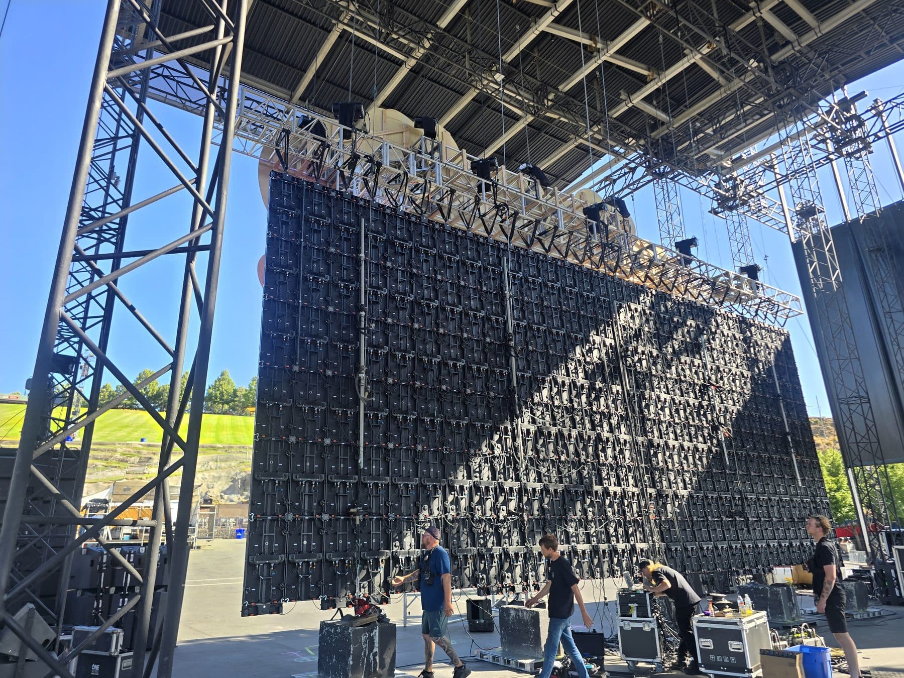 Rear of a large LED wall mid-hang showing cabinet grid, rigging bars and cable runs